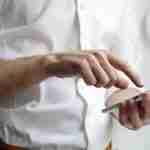 Person in a white shirt touching a phone screen